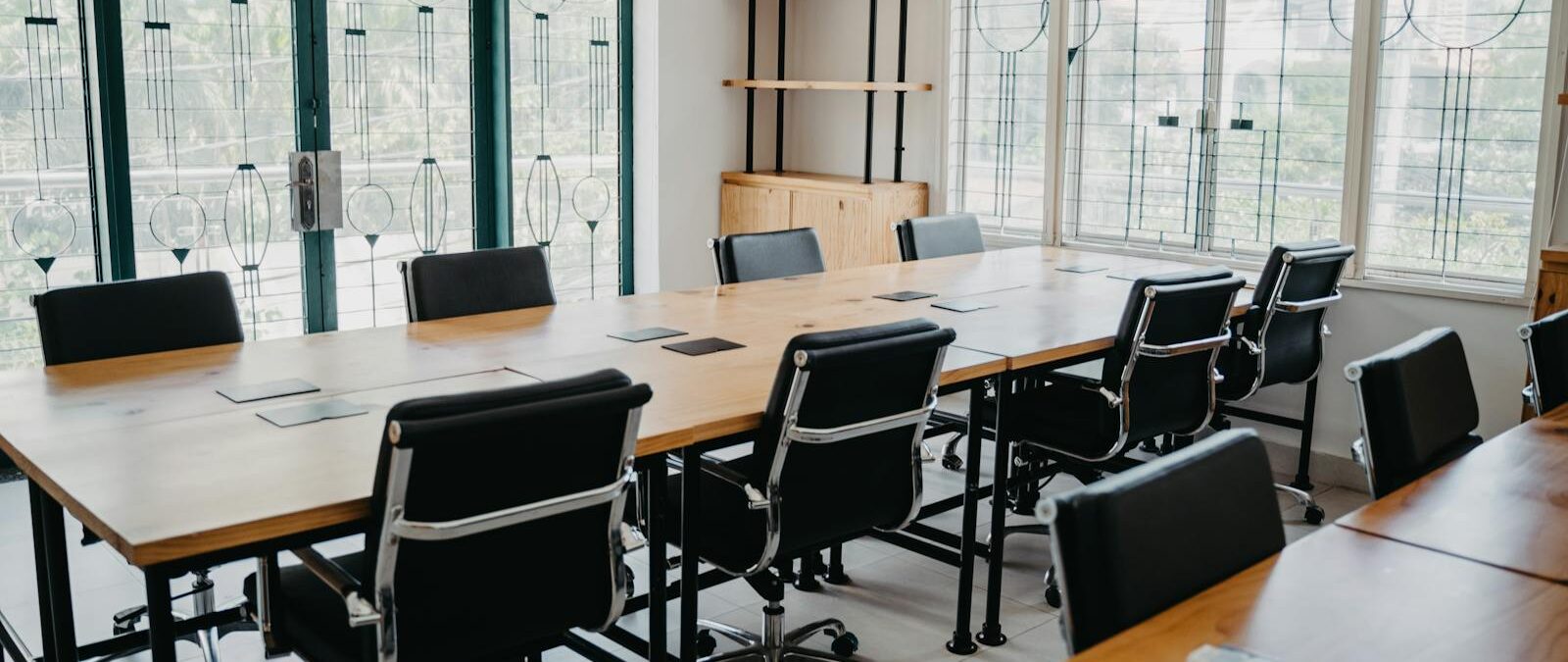 Spacious modern office conference room with black chairs and wooden tables.